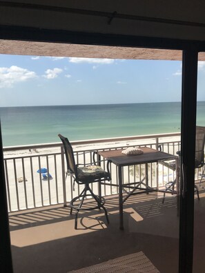 Un balcon avec une table, des chaises et une vue sur l’océan.