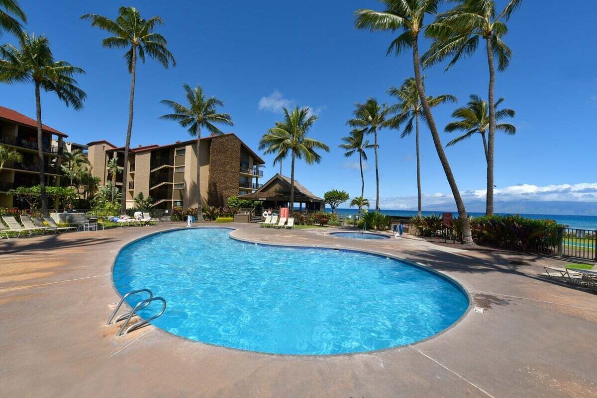 Una piscina di un resort con palme e vista sull'oceano.