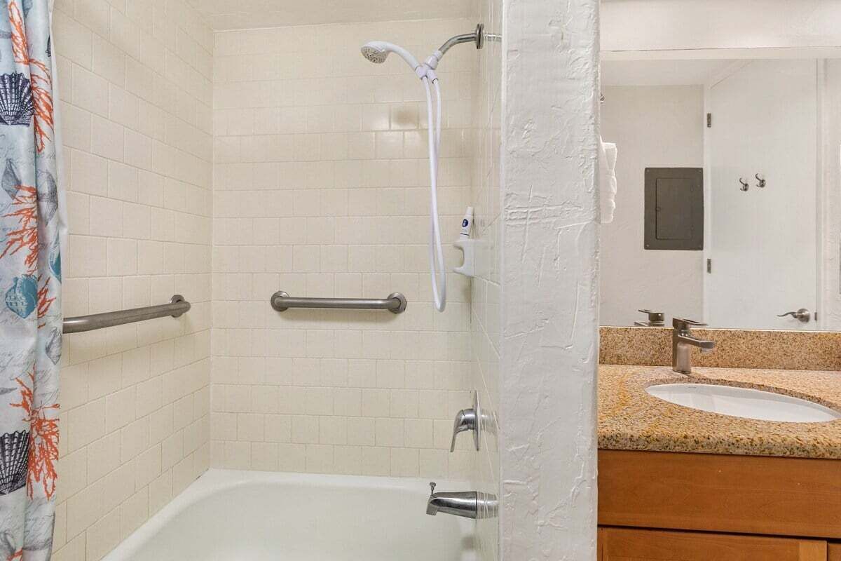 Une salle de bain équipée d’une baignoire, d’une douche et d’un lavabo avec un plan de travail en granit.