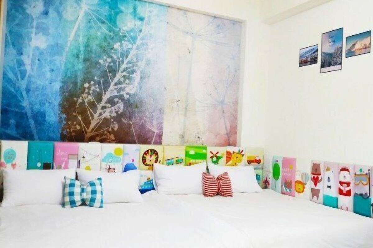 A room with a large abstract painting, a sofa with colorful cushions, and a wooden floor.