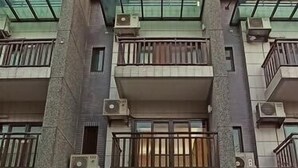 A multi-story building with balconies, a glass facade, and a ground-level entrance with a wooden door. - Tongxinyu Homestay (Wujie)