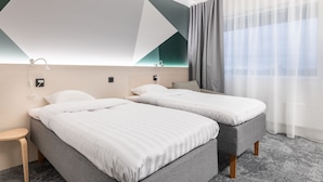 A modern hotel room with two single beds, a small table, and a large window with sheer curtains. - GreenStar Hotel Vaasa (Vaasa)