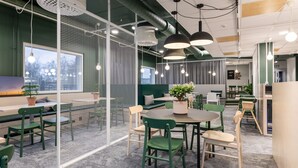 A modern office space with green and white furniture, round tables, and hanging pendant lights. - GreenStar Hotel Vaasa (Vaasa)
