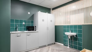 A modern kitchen with a white refrigerator, microwave, and sink. - GreenStar Hotel Vaasa (Vaasa)
