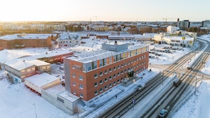 A multi-story hotel with a red brick facade, located near a snow-covered parking lot and busy roads. - GreenStar Hotel Vaasa (Vaasa)