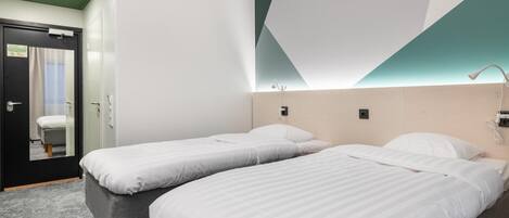 Habitación de hotel con dos camas individuales, techo verde, espejo y una puerta con un cartel.