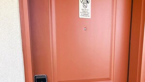 Une porte rouge sur laquelle est apposé un panneau d’interdiction concernant le tabac, les cigarettes électroniques et le cannabis.