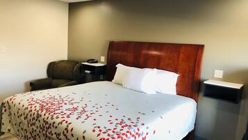 Une chambre d’hôtel avec un grand lit, une tête de lit en bois, un bureau avec un téléphone, une chaise et une table de chevet.