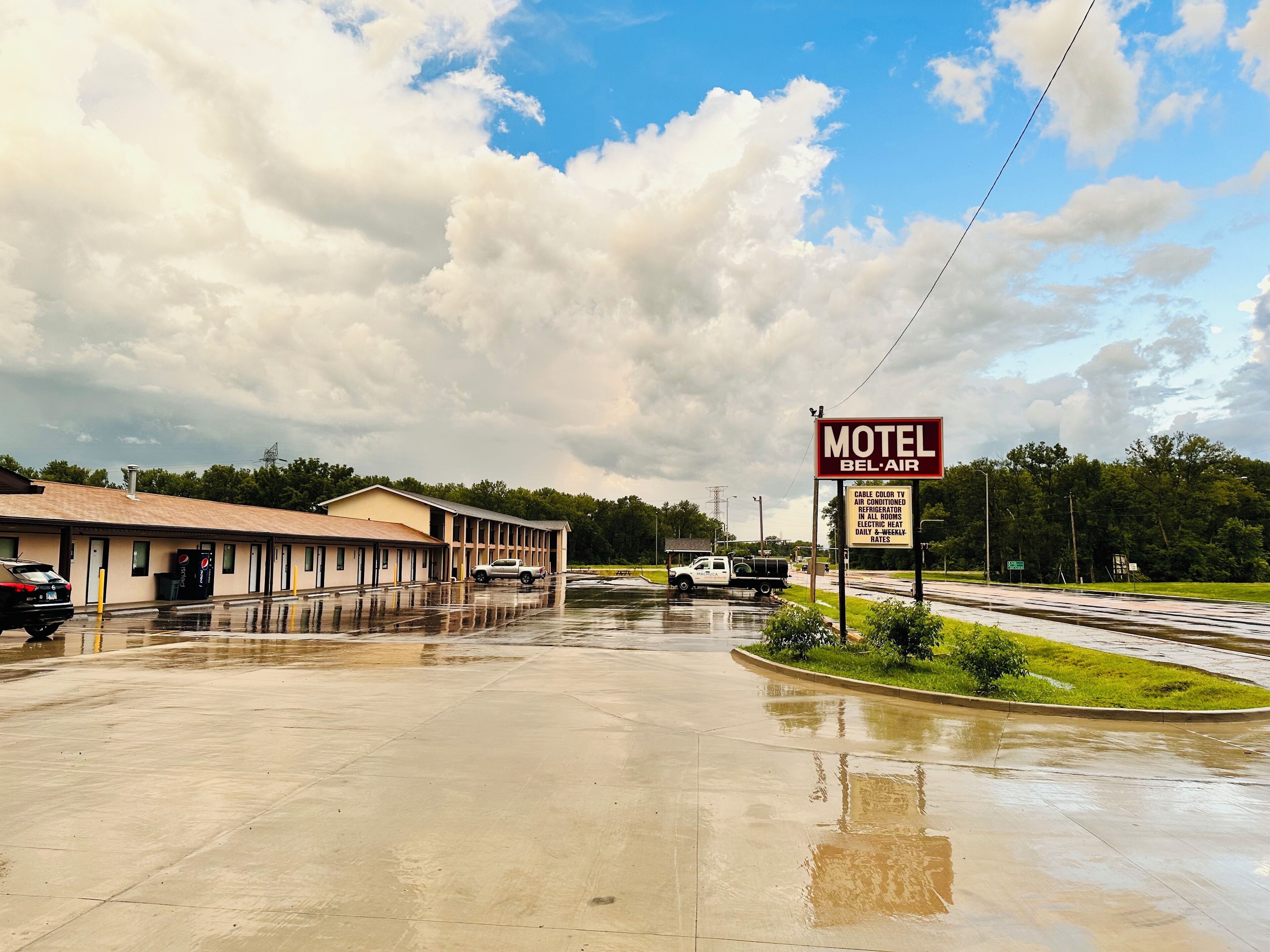 A motel with a signboard advertising amenities like cable TV, air conditioning, and an electric heater.