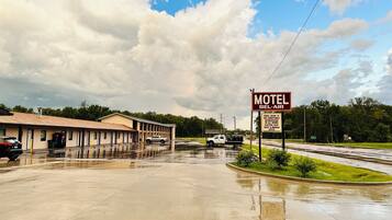 A motel with a signboard advertising amenities like cable TV, air conditioning, and an electric heater.