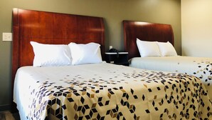 Une chambre d’hôtel avec deux lits, chacun doté d’une tête de lit en bois, de draps blancs et d’une couvre-lit à motifs.