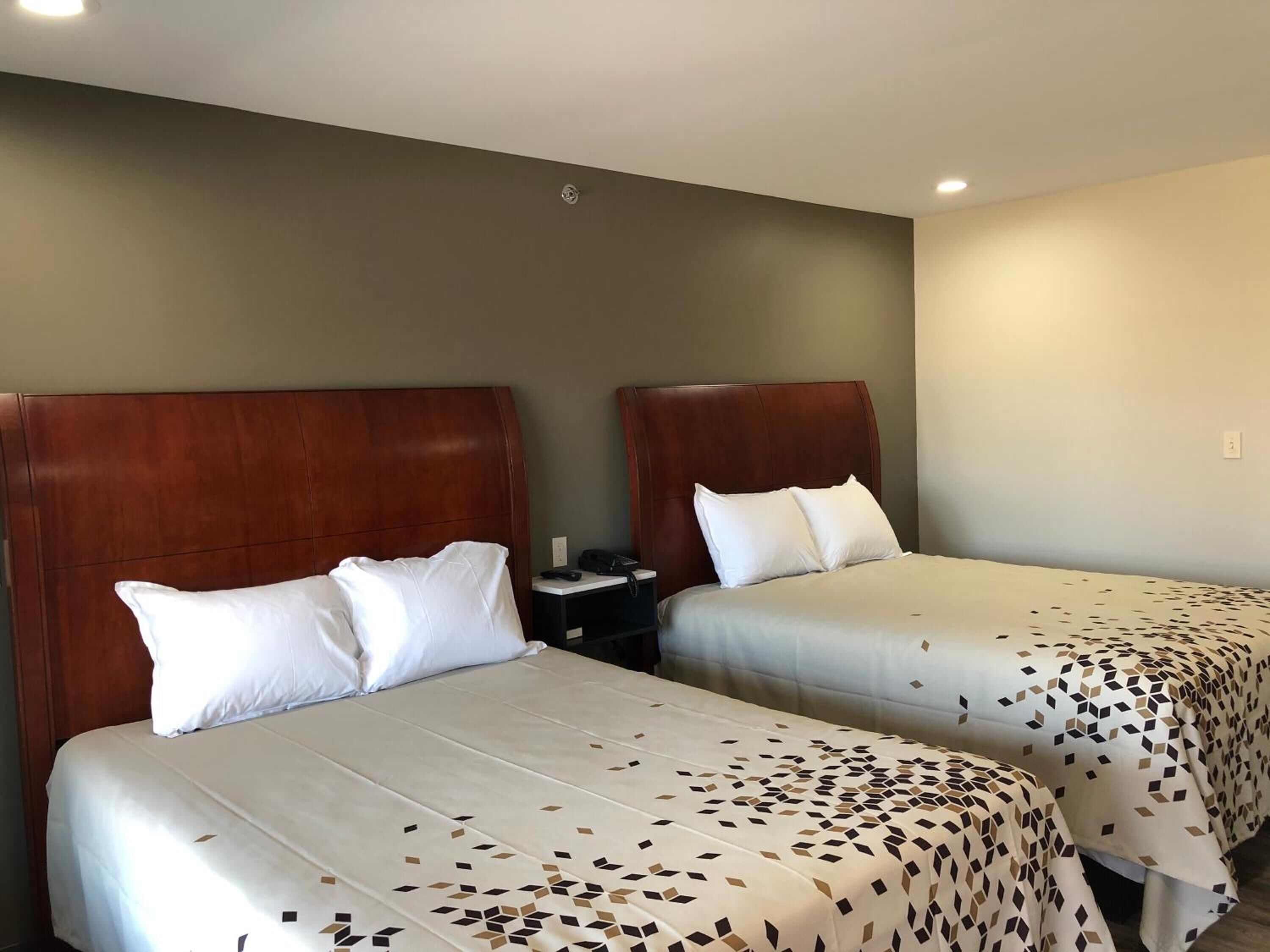 Une chambre d’hôtel avec deux lits, chacun doté d’une tête de lit en bois et de linge de lit blanc.