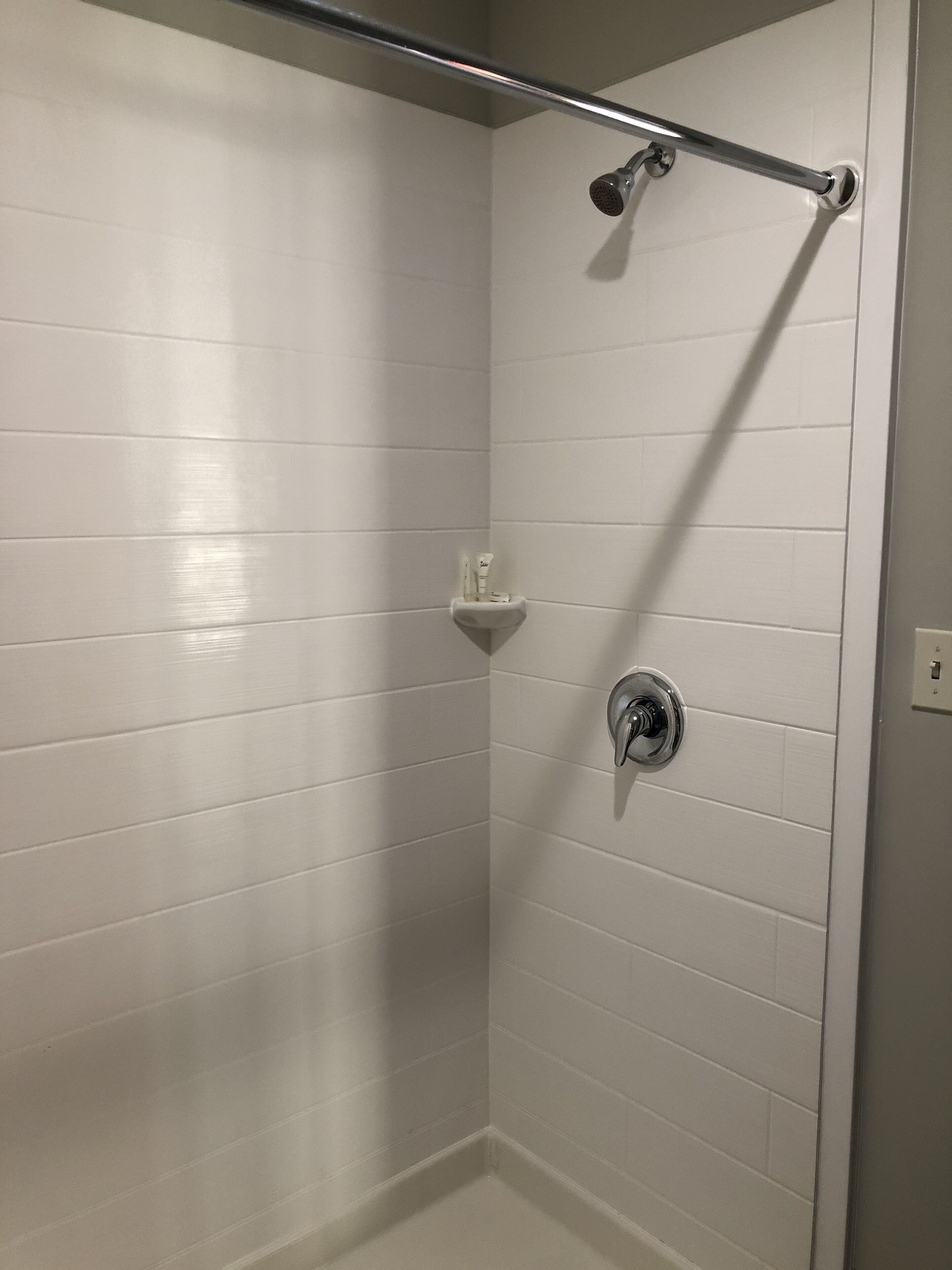 A shower with a handheld showerhead and a handheld shower bar.