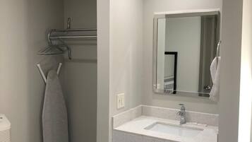 Un baño moderno con lavamanos, espejo y barra para toallas blancos.