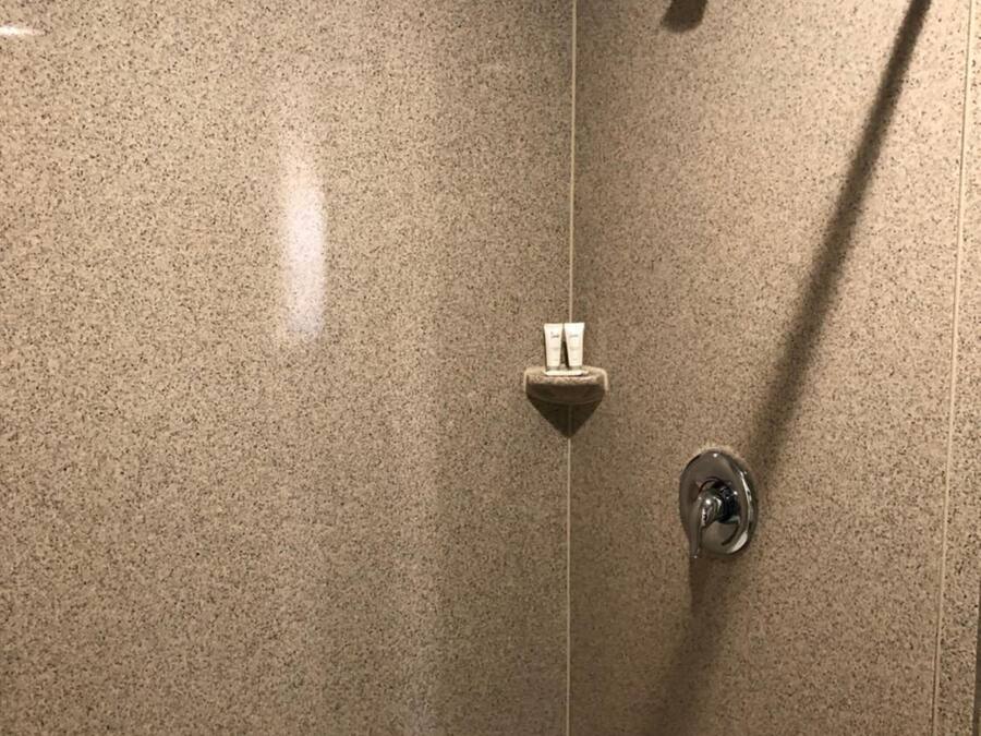 Une douche équipée d’un pommeau de douche à main et d’un robinet fixé au mur.