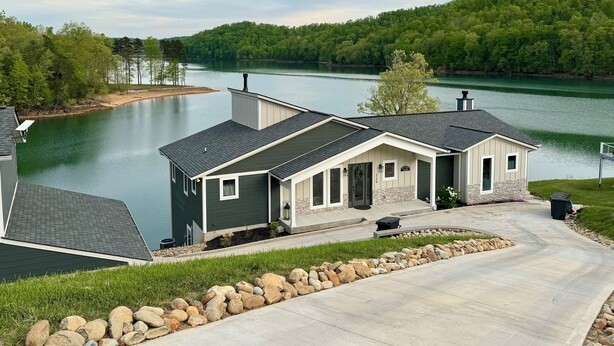 Ein zweigeschossiges Haus mit Steinfundament, dunklem Dach und einer Auffahrt zu einer Garage.
