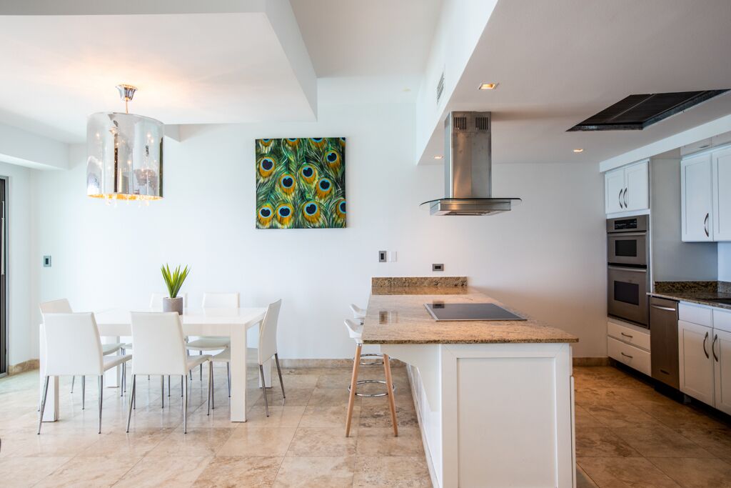 A modern kitchen with white cabinetry, a granite countertop, and a stainless steel range hood.