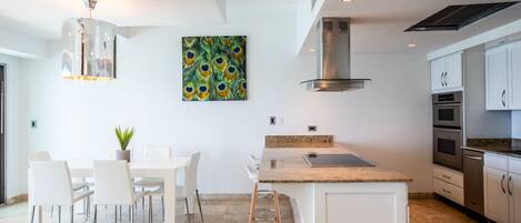 A modern kitchen with white cabinetry, a granite countertop, and a stainless steel range hood.