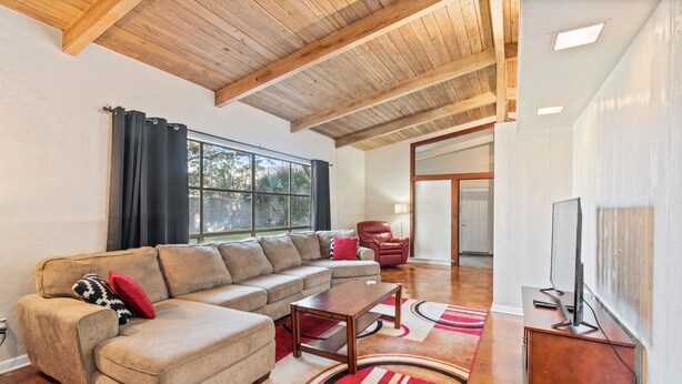 A living room with a sectional sofa, a wooden coffee table, and a television on a stand. - Mid-Century Vibes w/ Firepit Near UF/Downtown/Shands & Walk to Coffee Culture (Gainesville)