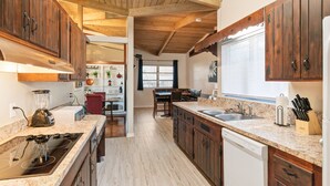 A kitchen with wooden cabinets, a granite countertop, a dishwasher, and a window with blinds. - Mid-Century Vibes w/ Firepit Near UF/Downtown/Shands & Walk to Coffee Culture (Gainesville)
