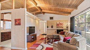 A spacious living room with a large sofa, wooden flooring, and a fireplace. - Mid-Century Vibes w/ Firepit Near UF/Downtown/Shands & Walk to Coffee Culture (Gainesville)