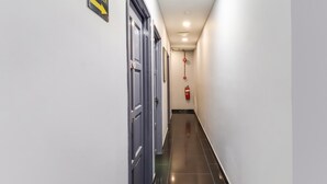 A hallway with doors on the left, a fire extinguisher on the right, and a sign indicating a direction. - OYO 89381 Moonnight Hotel (Batu Caves)