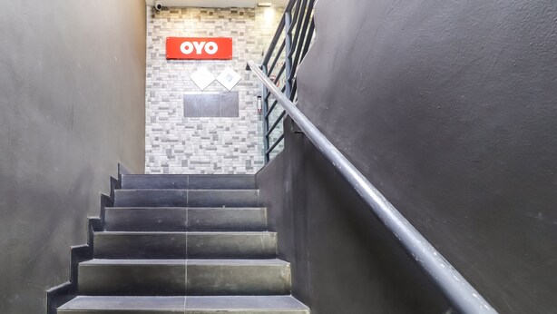 A staircase with a metal handrail leading to a room with a 'OYO' sign on the wall. - OYO 89381 Moonnight Hotel (Batu Caves)