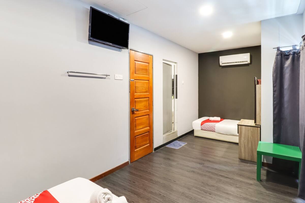 Een hotelkamer met een bed, een televisie, een houten deur, een spiegel en een groene stoel.