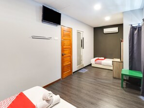 A hotel room with a bed, a TV, a wooden door, a mirror, and a green chair. - OYO 89381 Moonnight Hotel (Batu Caves)