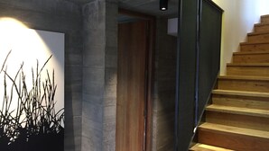 A staircase with wooden steps and a metal railing, leading to a wooden door.