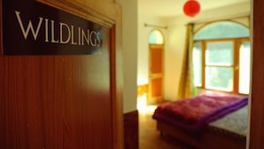A room with a bed, a window, and a door labeled "WILDINGS". - Nomads Hostel (Bhuntar)