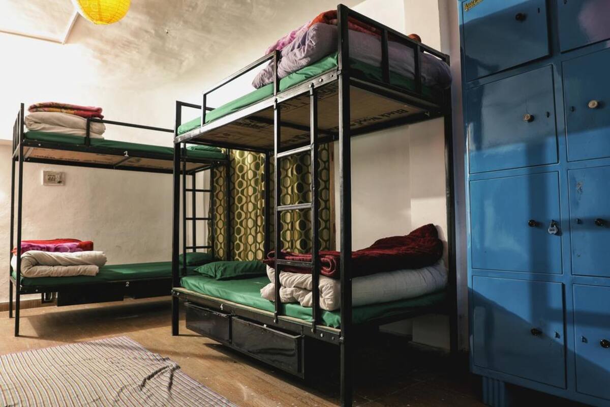 Une chambre de dortoir avec des lits superposés, un meuble de rangement bleu et un mur à motifs.