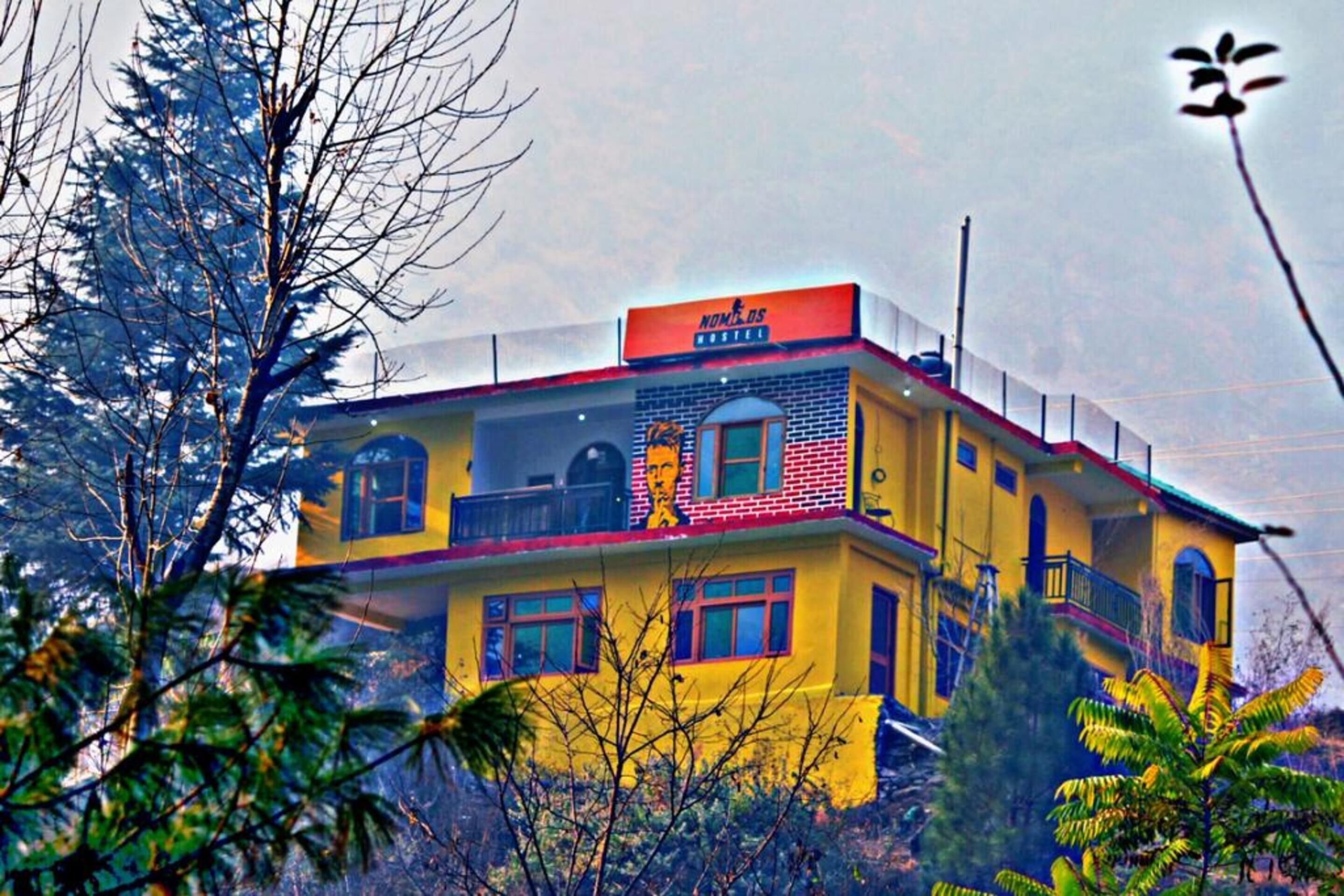 Un edificio de dos plantas con fachada amarilla y tejado rojo.