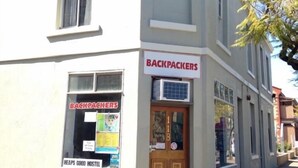 A building with a sign reading "BACKPACKERS" and a window with a poster advertising "HEAPS GOOD HOSTEL". - Shingos Backpackers (Adelaide)