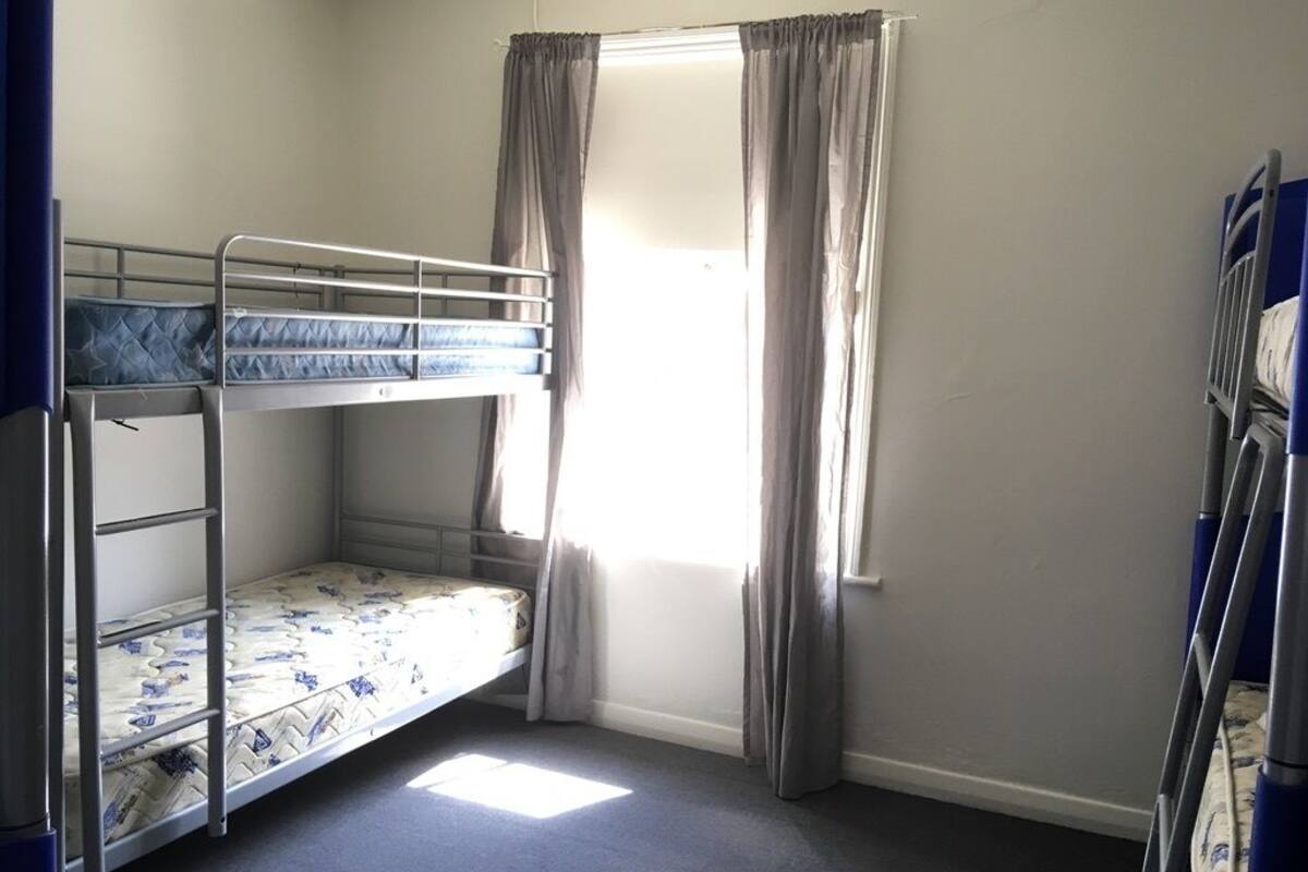 A bunk bed room with a window and curtains.