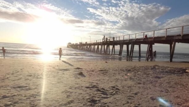 A beach with a pier extending into the ocean. - Shingos Backpackers (Adelaide)