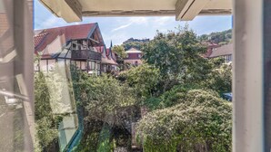 A view of traditional European-style buildings with red-tiled roofs, surrounded by lush greenery.