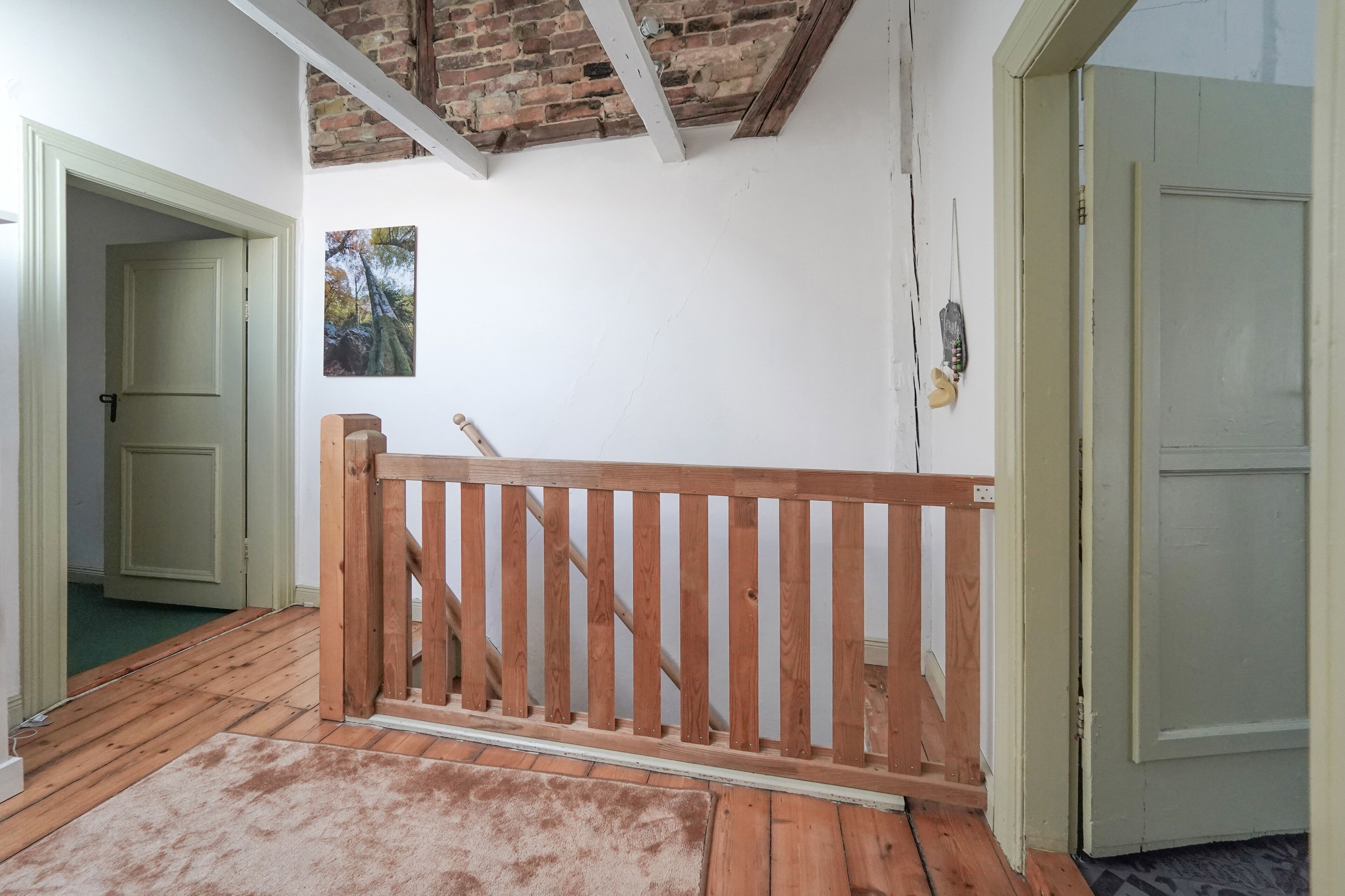 Una habitación con barandilla de madera, puerta verde y techo de ladrillo.