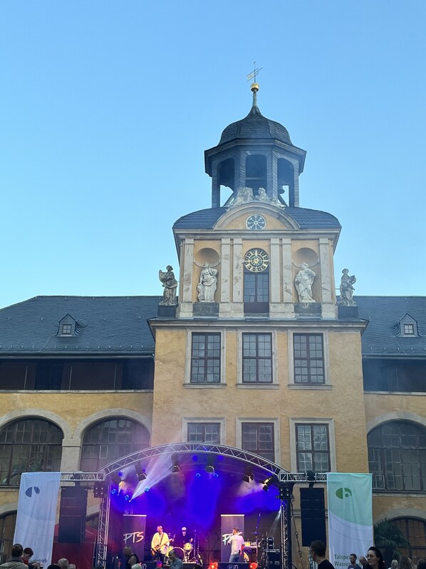 A building with a clock tower, arched windows, and statues.