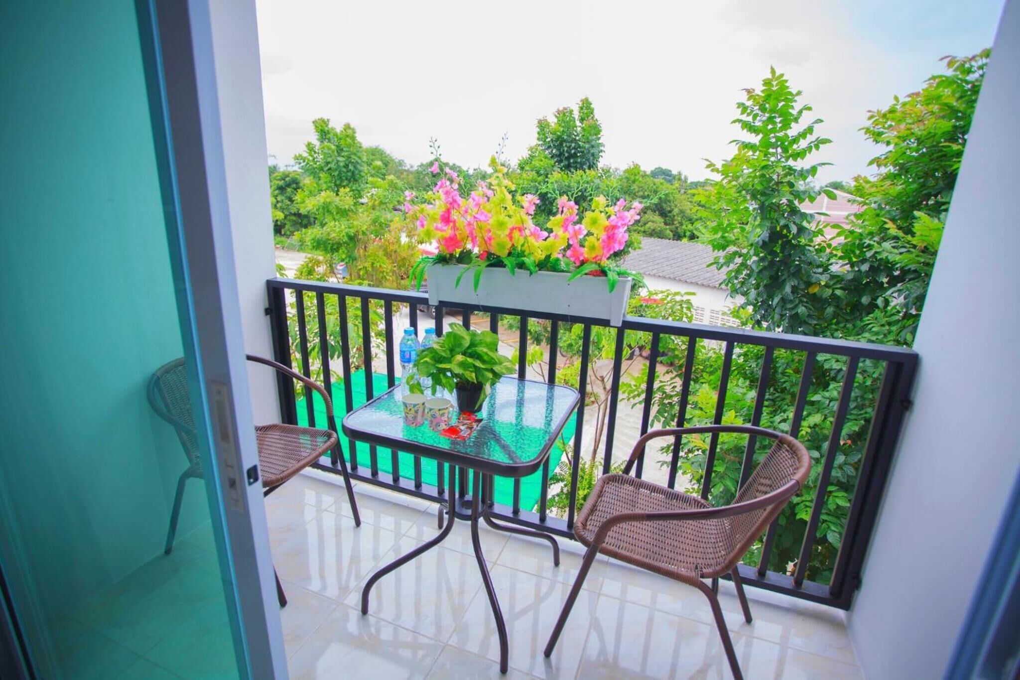 Ein Balkon mit zwei Korbstühlen, einem kleinen Tisch und einem Blumentopf sowie einem Blumenkasten.