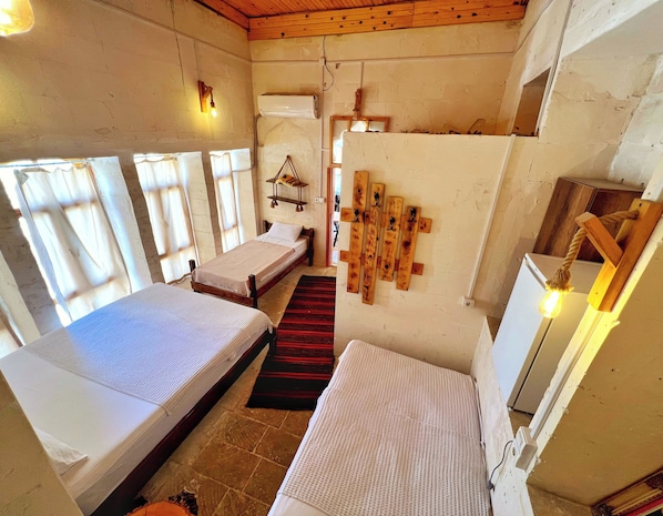 Una habitación con dos camas, techo de madera, alfombra roja y un perchero de madera en la pared.