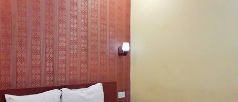 A hotel room with a large bed, a wooden headboard, and a patterned wall.