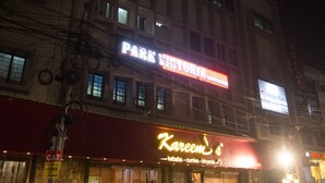 A building with a brightly lit sign for "Park Tenisori" and "Kareem's" restaurant. - Hotel Park Victoria (Kolkata)