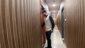A man in a hallway with wooden paneling and a tiled floor. - Hotel Park Victoria (Kolkata)