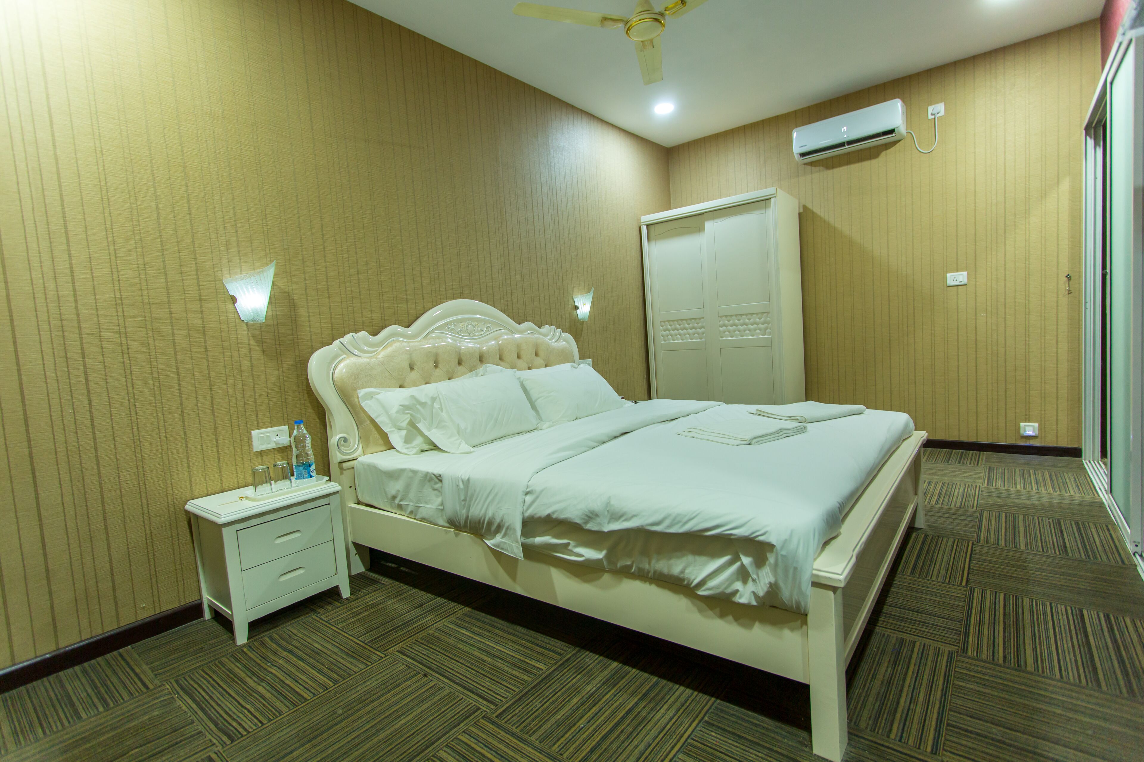 A hotel room with a bed, nightstand, and wardrobe.