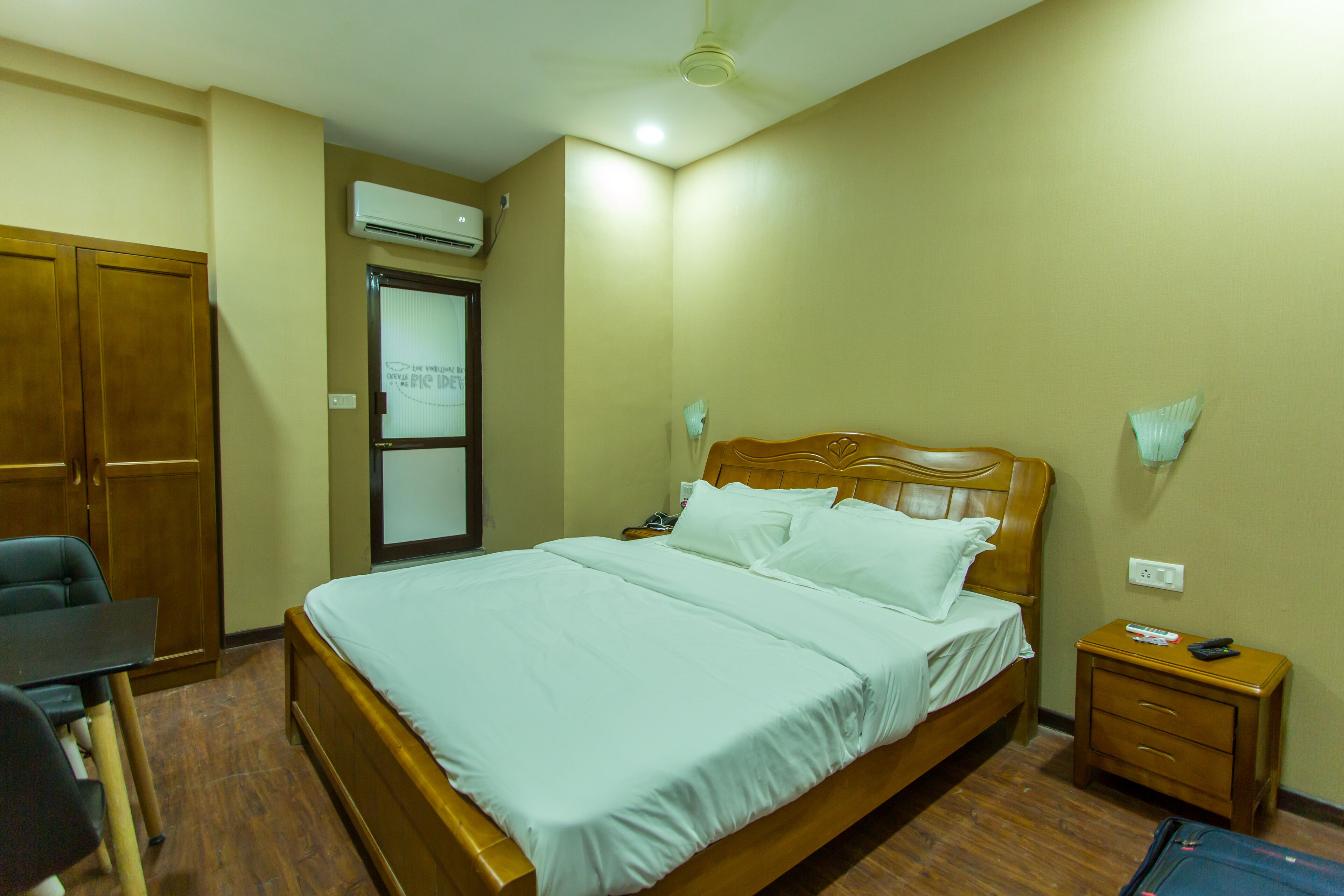 A hotel room with a bed, bedside table, nightstand, desk, and wardrobe.