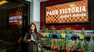Una persona de pie frente a un cartel que dice 'Park Victoria Guest House'.