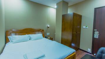 Una habitación de hotel con cama, armario, escritorio y silla.