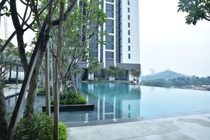Un edificio moderno con piscina, rodeado de árboles y vegetación.