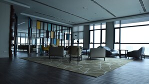 Une pièce spacieuse dotée d’une grande fenêtre, d’un tapis aux motifs géométriques et de meubles modernes.